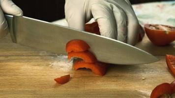 women's hands using a kitchen knife cut fresh red bell pepper on a wooden cutting board. Healthy eating. Chopped red bell pepper