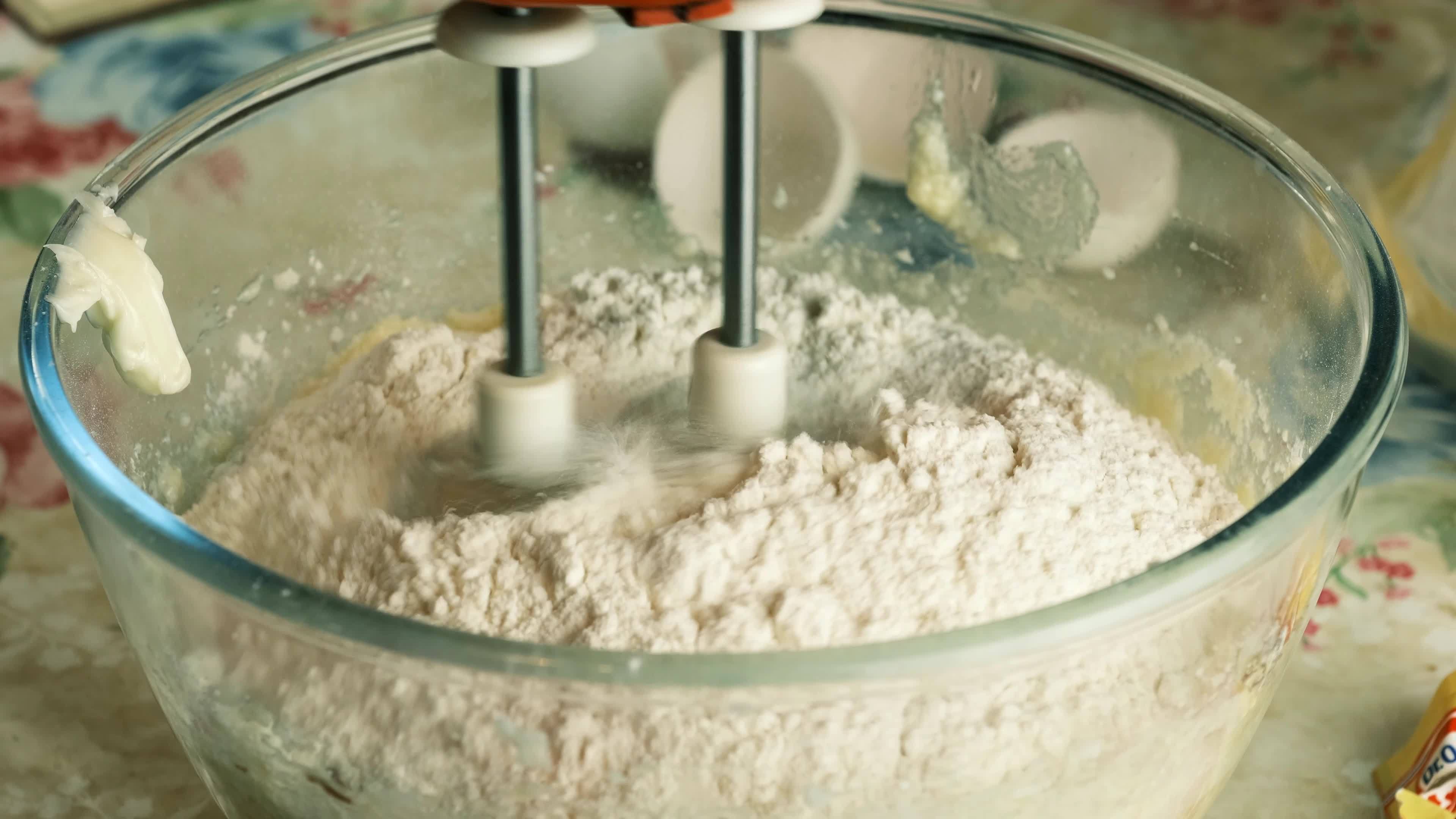 Kneading dough with hand electric mixer. Process of beating the dough