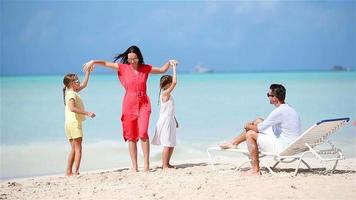 Young family on vacation have a lot of fun. Mother dancing on the beach with her beautiful kids