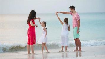 föräldrar och bedårande två barn har mycket roligt under sin sommarsemester på stranden. familj på fyra i kärlek, glad och vacker.