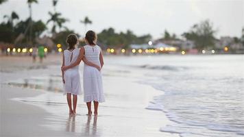 entzückende kleine kinder, die am strand spazieren gehen, mit einem wunderschönen bunten sonnenuntergang
