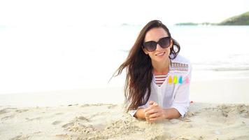 Young beautiful woman having fun on tropical seashore. Happy girl lying at white sand tropical beach. video