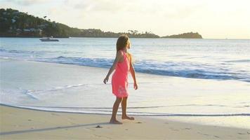 adorable niña activa en la playa blanca al atardecer. camara lenta video