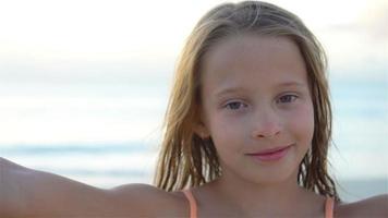 adorável menina fazendo selfie na praia branca tropical. câmera lenta video
