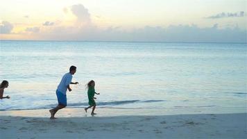 glücklicher vater mit kindern spielen am strand. glückliche familie, die spaß während der sommerstrandferien hat