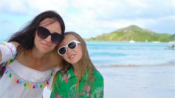 vacker mor och lilla dotter på karibiska stranden. familj tar selfie på den tropiska stranden. slow motion video