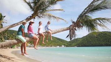 jong gezin op strandvakantie op palmboom. ouders en kinderen die samen plezier hebben aan de kust van het Caribisch gebied op antigua video