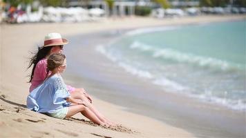 familj av mamma och barn njuta av havsutsikten på den vita stranden. familj avkopplande sittande på sanden video