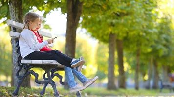 kleine schattige meisjes met mobiele telefoon in de herfst. kinderen hebben plezier op een warme zonnige herfstdag buitenshuis video