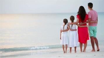 jovem família de quatro pessoas em férias na praia no pôr do sol video