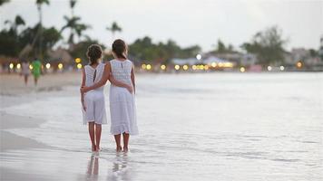 entzückende kleine kinder, die am strand spazieren gehen, mit einem wunderschönen bunten sonnenuntergang
