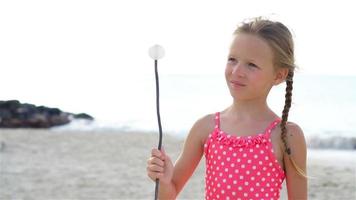 bedårande liten flicka på stranden som har mycket roligt. slow motion video