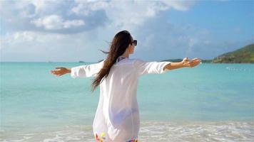 Young beautiful woman having fun on tropical seashore. Happy girl walking at white sand tropical beach. SLOW MOTION video