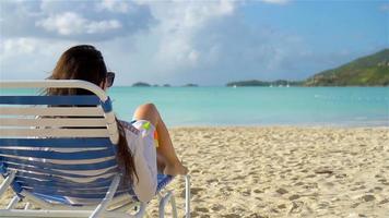 mujer tomando el sol en una tumbona en la playa blanca tropical video