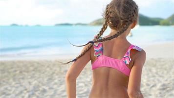 adorável menina correndo na praia tropical durante as férias em câmera lenta video