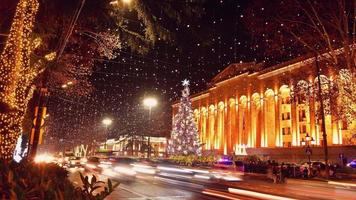 Cars in traffic on rush hours at night in rustaveli avenue in capital city Tbilisi in Georgia on xmas with xmas tree by parliament on background