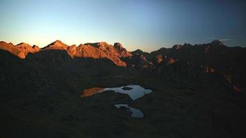 Las luces del amanecer de la mañana de 8k se reflejan en los picos de las montañas video
