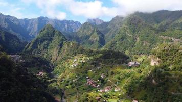luchtfoto drone uitzicht op een bergdorp op het eiland madeira, portugal. levendige kleuren. bergketen op de achtergrond. landelijke vakanties. wolken met zon. de wereld rondreizen. ontspannend gevoel. video