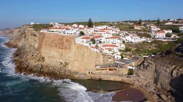 Luftdrohnenansicht eines natürlichen Pools im Ozean, neben der Klippe und einem Küstendorf an einem sonnigen Tag. azenhas do mar, portugal. Sommerferien und Reisen. das Leben genießen. leuchtende Farben. video