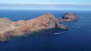 vista aérea de drones de una hermosa isla en medio del océano. colores vibrantes. olas rompiendo contra los acantilados. viajar y explorar. vacaciones. barcos que pasan en el océano. video