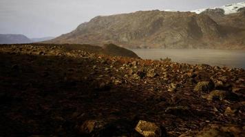 río claro con rocas conduce hacia las montañas iluminadas por la puesta de sol video