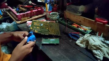 mann, der elektronik in einer werkstatt voller mechanischer ausrüstung repariert video