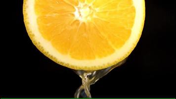 fresh juice extraction of orange fruit on black background video