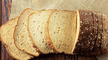 Volkoren gesneden biologisch brood bestaande uit haver en lijnzaad op houten tafel. gezond dieet video