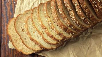 pão orgânico fatiado integral composto de aveia e sementes de linho na mesa de madeira. dieta saudável video