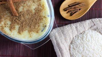 rice pudding with cinnamon on wooden table, accompanied by wooden spoon and cinnamon splinters video