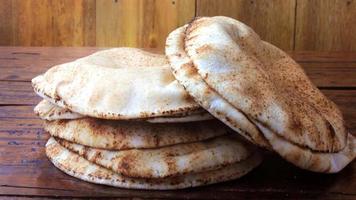 pão pita isolado na mesa de madeira rústica. comida tradicional e típica da cozinha árabe video