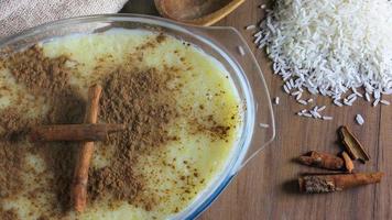 rice pudding with cinnamon on wooden table, accompanied by wooden spoon and cinnamon splinters video