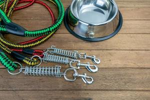 Pet leashes with hook and stainless bowl on wooden table.  Pet accessories concept photo