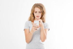 Young beautiful woman in t shirt using her smartphone isolated on white background. Sexy blond girl chating with friend or shopping online. Copy space photo
