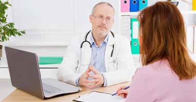 male doctor at the table communicates with the patient photo