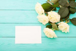 White roses on blue wooden background with copy space photo