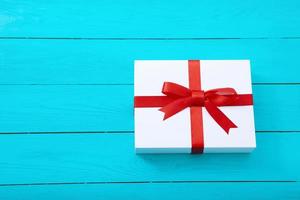 Fashionable gift box on blue wooden background with copy space. Selective focus. photo