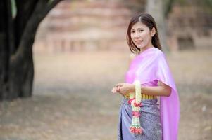 atractivas mujeres tailandesas con vestimenta tradicional tailandesa sostienen guirnaldas de flores frescas para ingresar a un templo basado en la tradición del festival songkran en tailandia foto