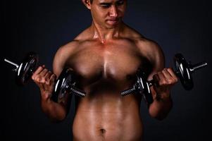 el hombre asiático fuerte levantó su mancuerna regularmente para mantener sus músculos fuertes y hermosos foto
