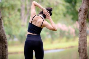 una hermosa mujer asiática se está calentando, para flexibilizar los músculos antes de ir a correr