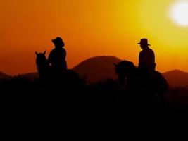 The Western Cowboy forced his horses to stop while the sun was setting, In lands where the law has not yet reached photo