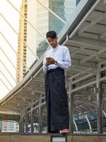 Young Burmese businessman using mobile phone to find a data for his business