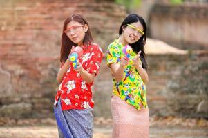 Hermosas mujeres asiáticas sostienen pistolas de agua de plástico en un antiguo templo durante Songkran, el festival de agua más hermoso y divertido de Tailandia foto