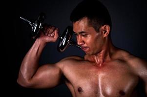 The strong Asian man lifted his dumbbell regularly to keep his muscles strong and beautiful