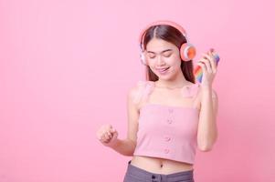 hermosas chicas asiáticas escuchan música en línea a través de la conexión a Internet de su teléfono móvil y bailan alegremente foto