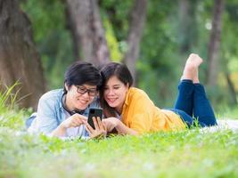 las parejas lgbt asiáticas se relajan en el parque mientras escuchan música en sus teléfonos móviles foto