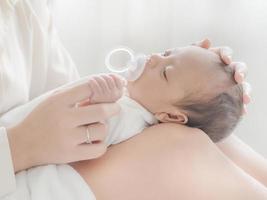 una hermosa mujer asiática pone a su bebé recién nacido en su cuerpo foto