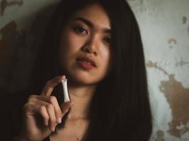 una joven adolescente asiática usa un tubo de plástico que contiene drogas blancas para vender a clientes adictos