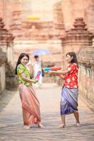 Hermosas mujeres asiáticas sostienen pistolas de agua de plástico en un antiguo templo durante Songkran, el festival de agua más hermoso y divertido de Tailandia