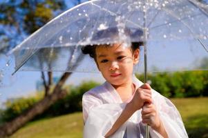 una niña estaba felizmente parada en un paraguas contra la lluvia foto